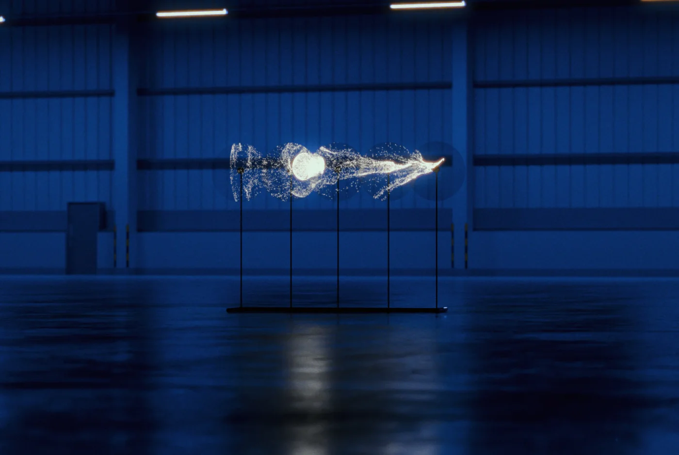Les cinq hélices sur leur structure au sol composent une longue traînée blanche dans un hangar bleu, reflétée par le sol.